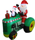 Santa and a penguin riding a green tractor inflatable