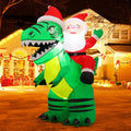 Santa riding a green T. rex in a Santa hat, inflatable in front of a lit house