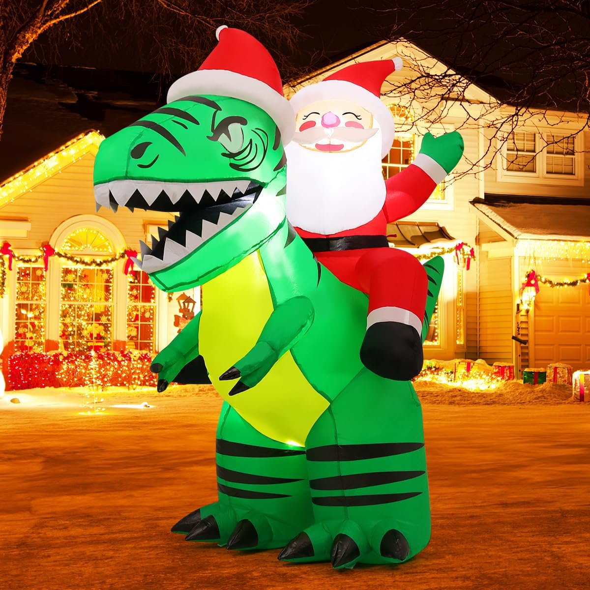 Santa riding a green T. rex in a Santa hat, inflatable in front of a lit house