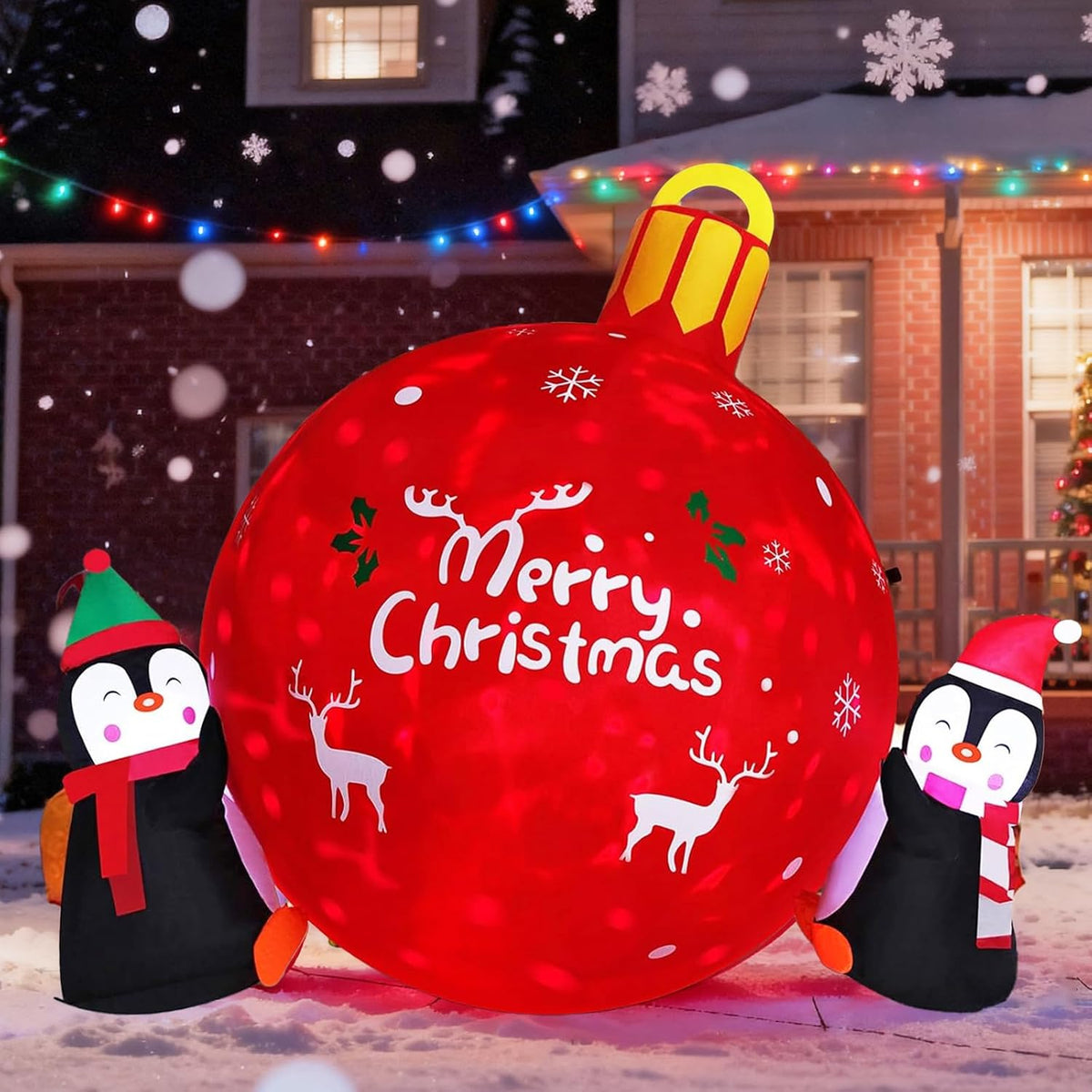 Two penguins in Santa hats pushing a big red Merry Christmas ornament inflatable in the snow