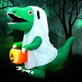 Green dinosaur inflatable in a white ghost sheet costume holding a pumpkin pail at night