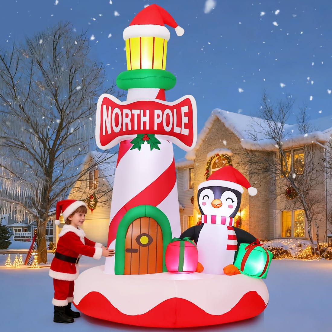 Red and white striped North Pole lighthouse inflatable with a penguin and a small Santa figure in the snow
