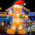 Giant gingerbread man inflatable in a Santa hat holding a candy cane and gift beside a posing couple