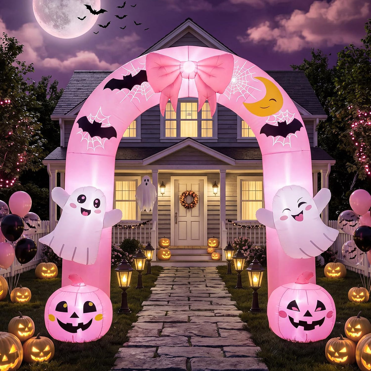 Pink Halloween arch inflatable with a bow, ghosts and jack-o'-lanterns over a front path at night