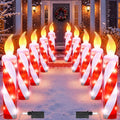 Rows of red and white candy cane candle pathway lights lining a snowy front walk