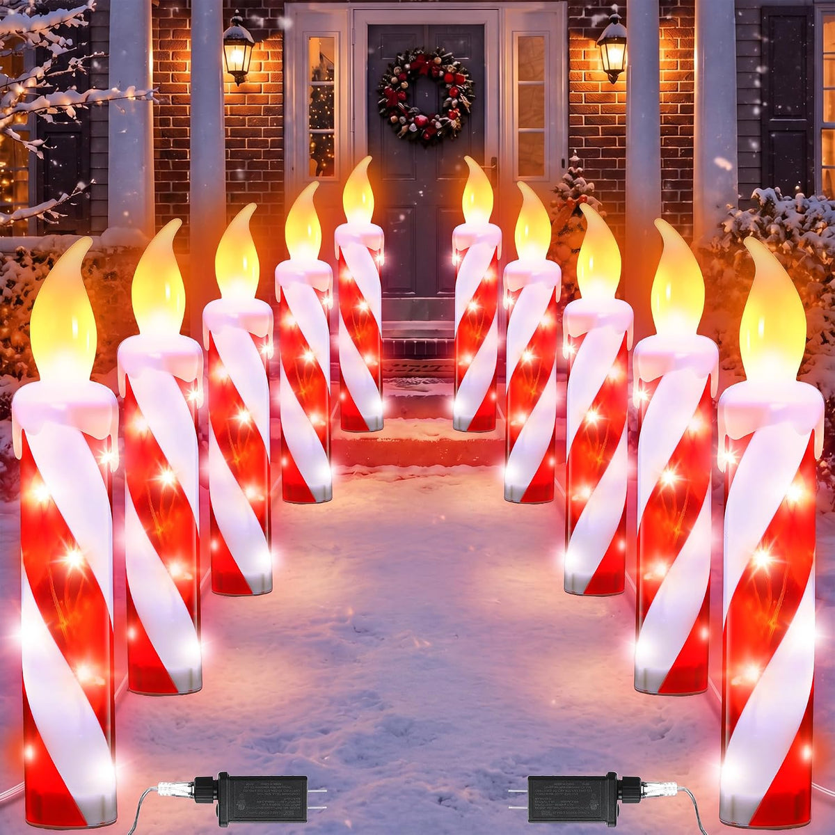Rows of red and white candy cane candle pathway lights lining a snowy front walk