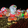 Mrs. Claus inflatable squatting with a candy cane barbell in a lit yard at night