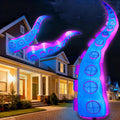 Tall glowing purple and blue octopus tentacle inflatables rising in front of a house at night