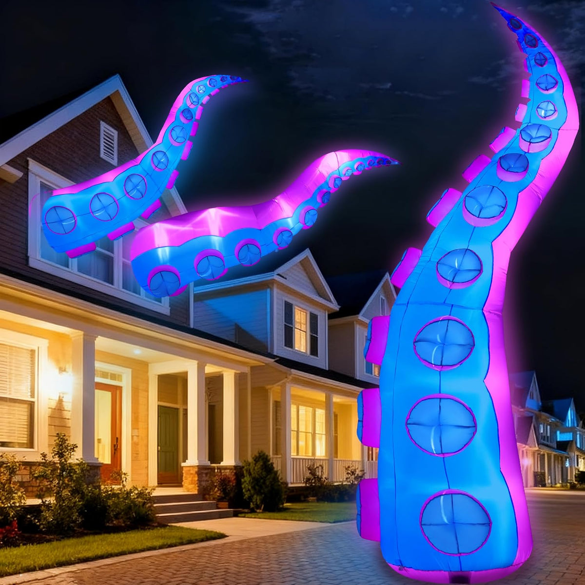 Tall glowing purple and blue octopus tentacle inflatables rising in front of a house at night