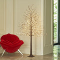 Brown twig tree covered in warm micro lights in a bright room corner