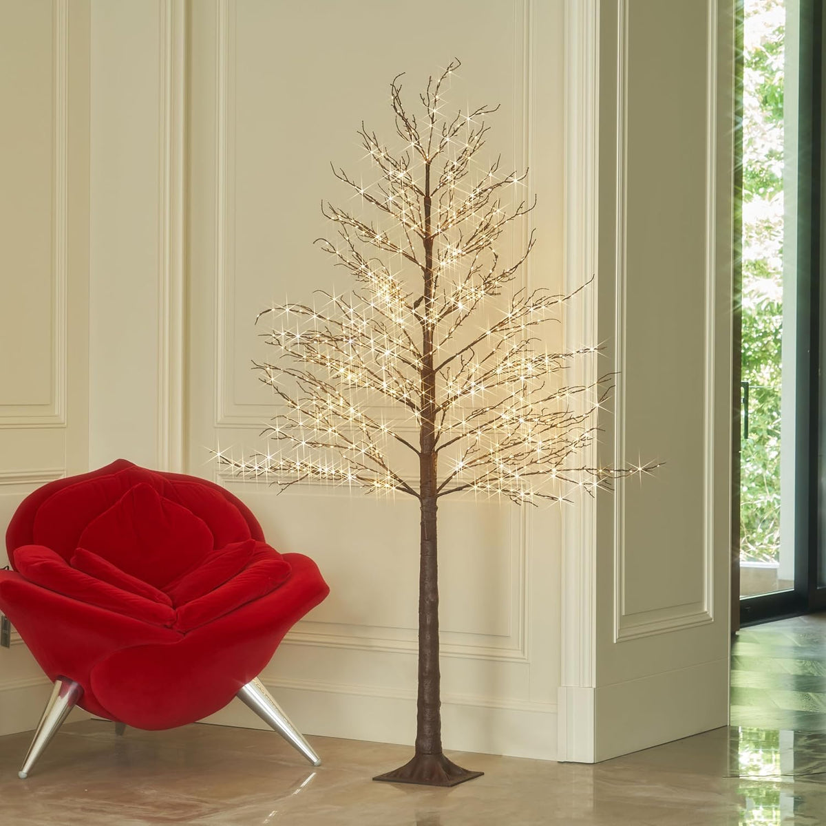 Brown twig tree covered in warm micro lights in a bright room corner
