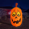 Tall orange pumpkin inflatable with a goofy face glowing at night