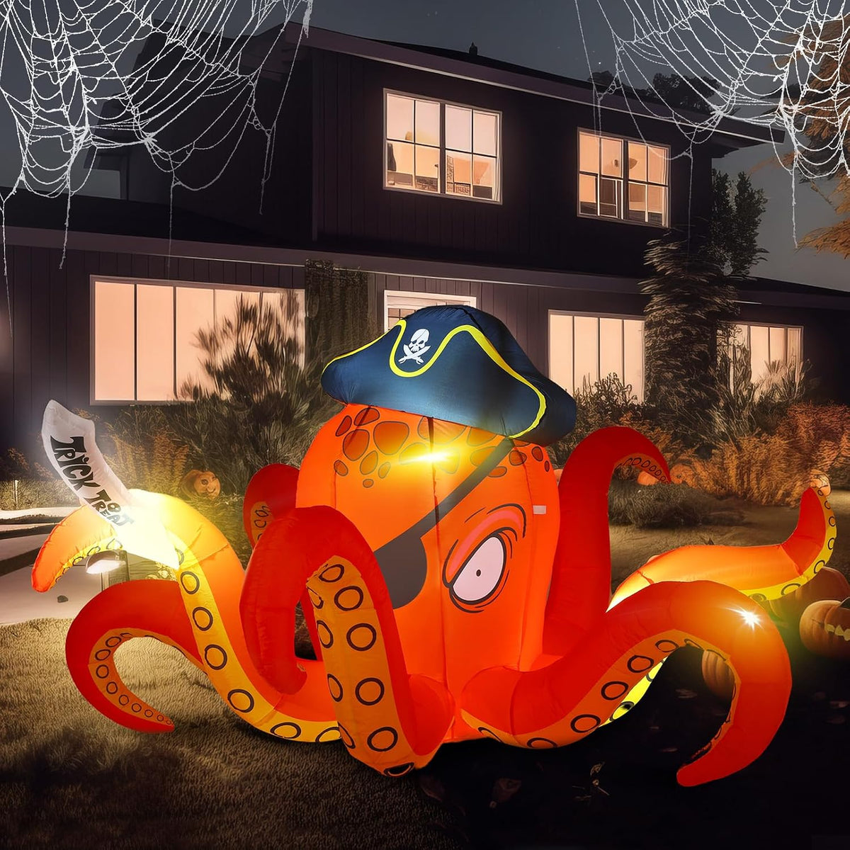 Orange octopus inflatable in a pirate hat and eye patch holding a cutlass at night