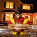 Small turkey inflatable in a pilgrim hat holding a Happy Thanksgiving banner in front of a lit house