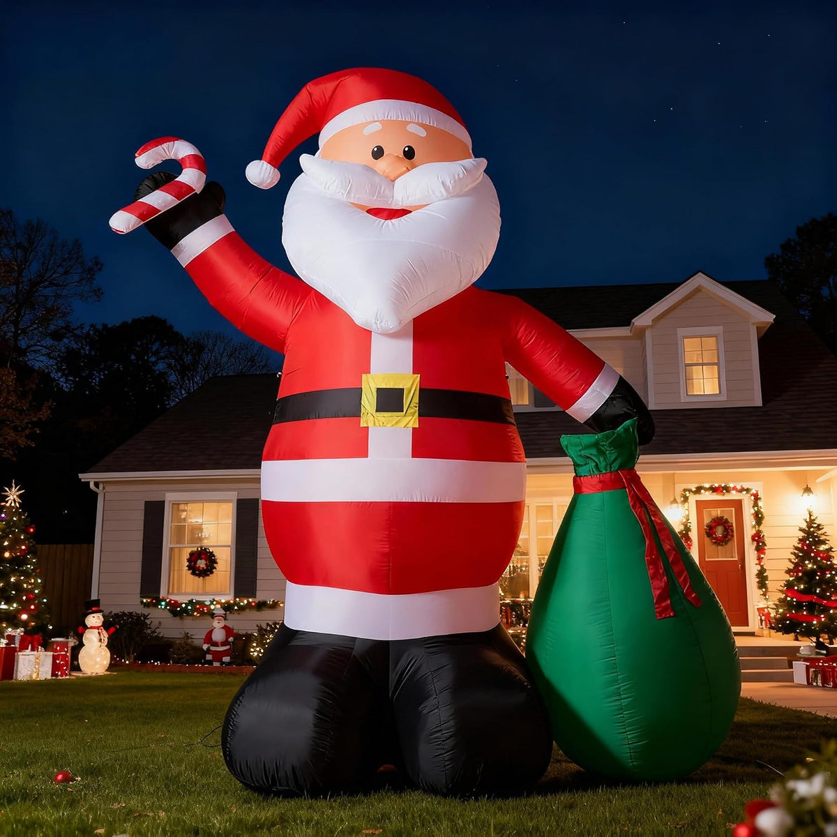 Giant Santa inflatable raising a candy cane with a green gift sack in front of a house at night