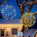 Multicolor and warm white solar light spheres hanging from a snowy tree with solar panels and remotes